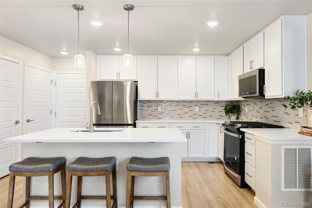 320 Marshall Mews, Superior, CO 80027 - kitchen featuring stainless steel appliances, a sink, a breakfast bar area, white cabinets, and light wood-style flooring