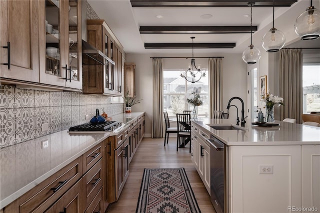 kitchen featuring a notable chandelier, a sink, light countertops, light wood-type flooring, and tasteful backsplash