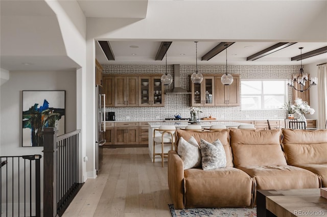 kitchen featuring wall chimney range hood, appliances with stainless steel finishes, light wood-style floors, light countertops, and open floor plan