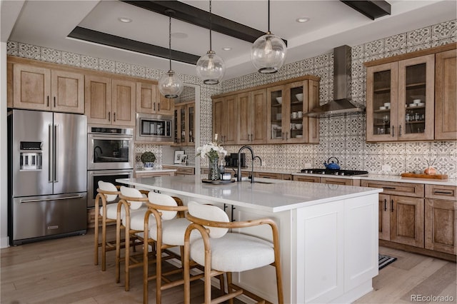 kitchen featuring a sink, wall chimney exhaust hood, appliances with stainless steel finishes, and light wood-style flooring