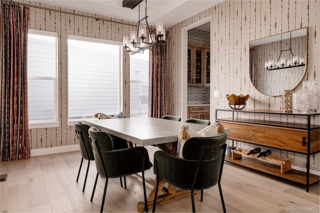 dining space featuring wallpapered walls, a notable chandelier, baseboards, and light wood-type flooring