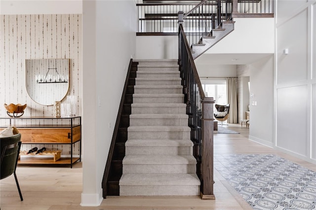 staircase with baseboards, a high ceiling, and wood finished floors