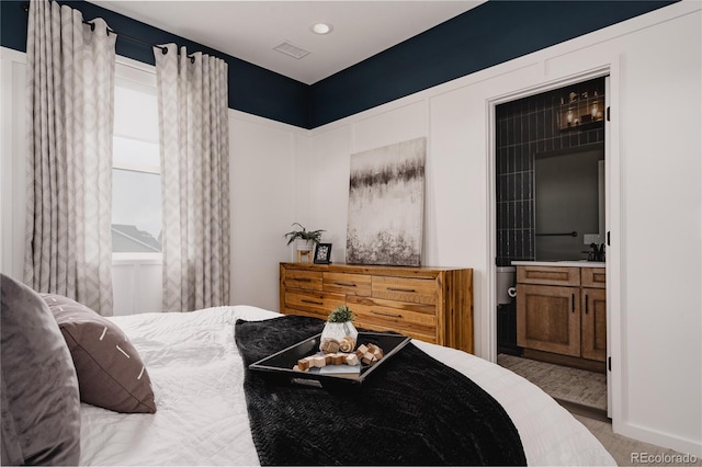 bedroom with carpet flooring, visible vents, and a sink
