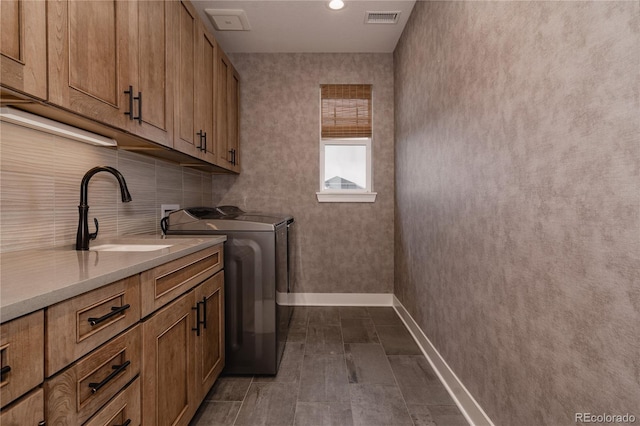 clothes washing area featuring cabinet space, washing machine and clothes dryer, a sink, baseboards, and visible vents