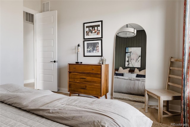 bedroom featuring arched walkways, visible vents, and wood finished floors
