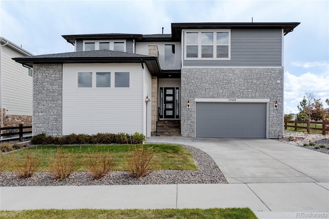 prairie-style home with an attached garage, fence, driveway, and stone siding