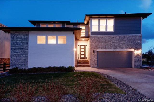 prairie-style home featuring stone siding, a garage, fence, concrete driveway, and entry steps