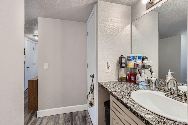 940 S Peoria St, Aurora, CO 80012 - bathroom with a textured ceiling, wood finished floors, vanity, baseboards, and a textured wall