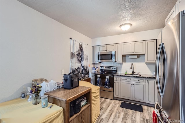 940 S Peoria St, Aurora, CO 80012 - kitchen featuring appliances with stainless steel finishes, a sink, a textured ceiling, and light wood finished floors