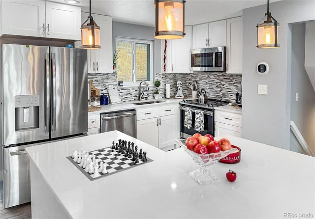 kitchen with sink, white cabinetry, tasteful backsplash, hanging light fixtures, and appliances with stainless steel finishes