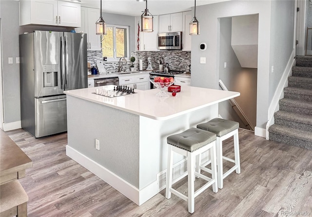 kitchen with sink, stainless steel appliances, a center island, white cabinets, and decorative light fixtures