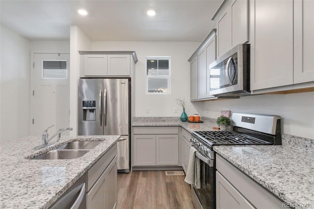 7017 Kali Ct, Frederick, CO 80530 - kitchen with appliances with stainless steel finishes, wood finished floors, gray cabinets, light stone counters, and recessed lighting