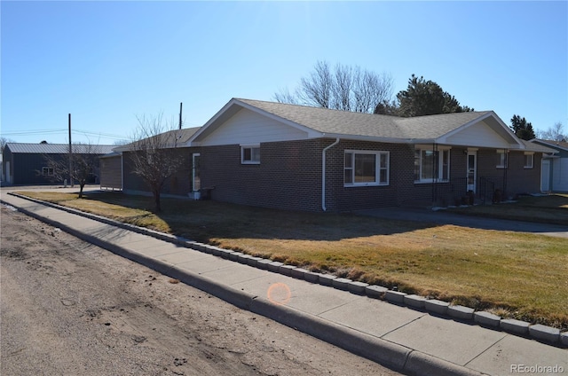 view of home's exterior with a yard, brick siding, and a shingled roof