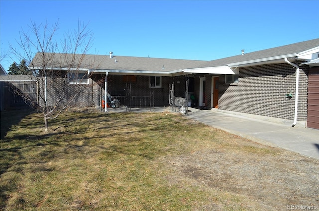 rear view of house featuring fence, a lawn, and brick siding