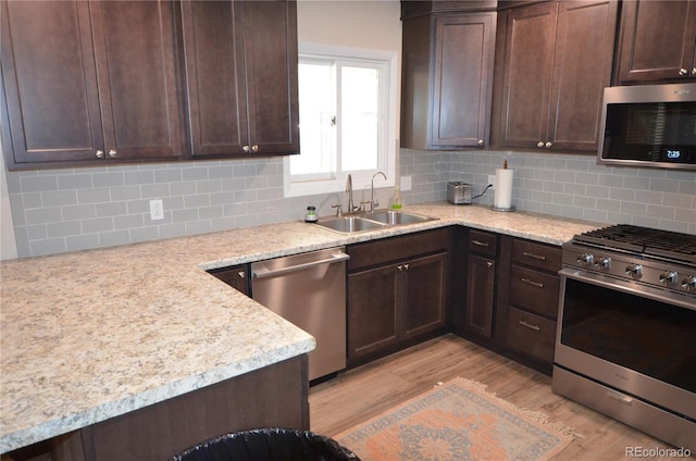 kitchen with light wood finished floors, appliances with stainless steel finishes, dark brown cabinets, and a sink