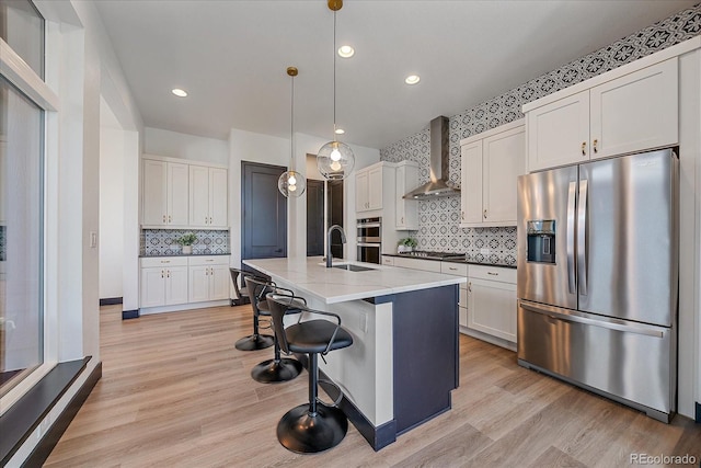 6047 N Nepal Ct, Aurora, CO 80019 - kitchen with stainless steel appliances, wall chimney range hood, decorative backsplash, light wood finished floors, and pendant lighting