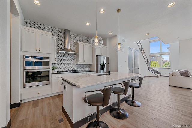 6047 N Nepal Ct, Aurora, CO 80019 - kitchen with wall chimney exhaust hood, appliances with stainless steel finishes, light wood finished floors, open floor plan, and recessed lighting