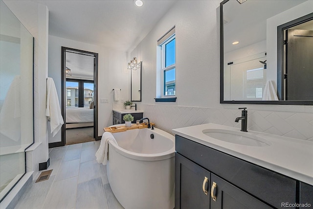 6047 N Nepal Ct, Aurora, CO 80019 - ensuite bathroom featuring a soaking tub, a shower stall, two vanities, recessed lighting, and tile walls