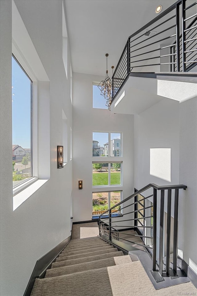 6047 N Nepal Ct, Aurora, CO 80019 - stairs with a towering ceiling, healthy amount of natural light, a chandelier, and carpet flooring