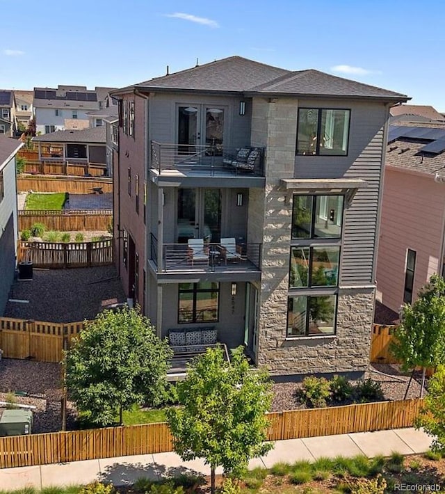 6047 N Nepal Ct, Aurora, CO 80019 - view of front of house with a balcony, stone siding, a fenced backyard, and a residential view