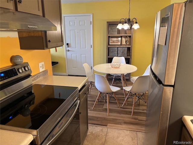 kitchen with appliances with stainless steel finishes, pendant lighting, light tile patterned floors, and a notable chandelier