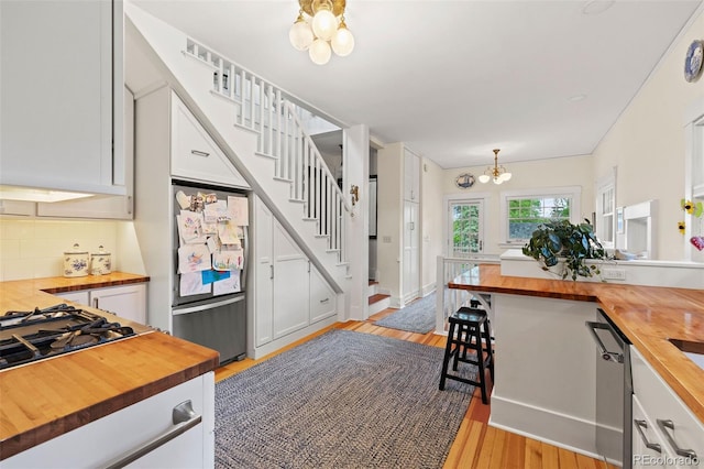 13 2nd St, Colorado Springs, CO 80906 - kitchen featuring wood counters, a chandelier, stainless steel appliances, tasteful backsplash, and white cabinetry