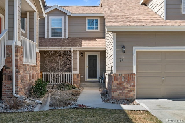 property entrance with a garage, covered porch, and a shingled roof