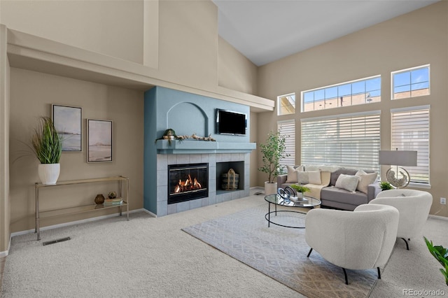 living room with baseboards, visible vents, high vaulted ceiling, a tiled fireplace, and carpet flooring