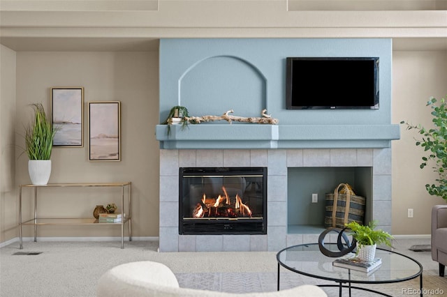 living area with a tiled fireplace, baseboards, and carpet floors