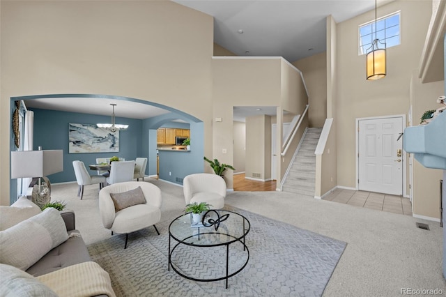 living area with baseboards, carpet, a chandelier, a high ceiling, and arched walkways