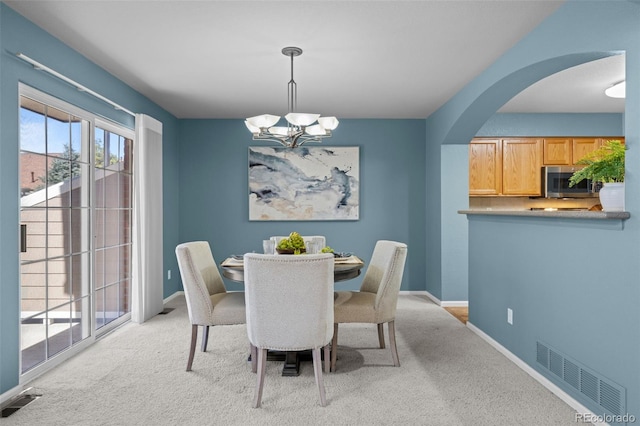 dining area featuring a notable chandelier, visible vents, and light carpet