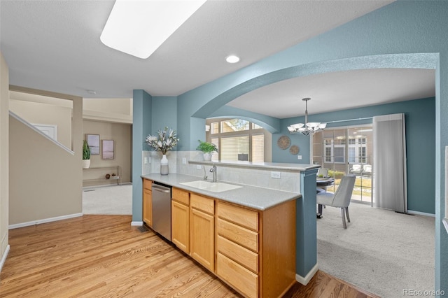 kitchen featuring light countertops, stainless steel dishwasher, an inviting chandelier, arched walkways, and a sink