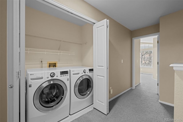 washroom featuring light colored carpet, baseboards, separate washer and dryer, and laundry area