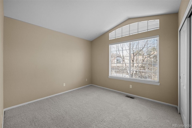 unfurnished room featuring visible vents, baseboards, lofted ceiling, and carpet