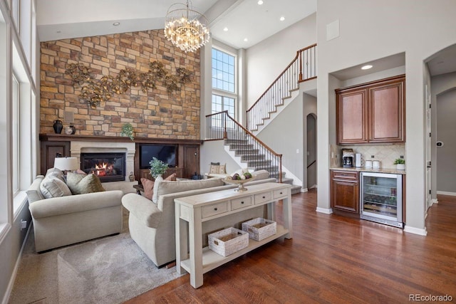 6299 Ellingwood Point Pl, Castle Rock, CO 80108 - living room featuring beverage cooler, high vaulted ceiling, arched walkways, a bar, and a glass covered fireplace