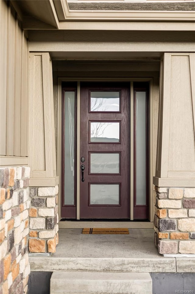 doorway to property with board and batten siding and stone siding