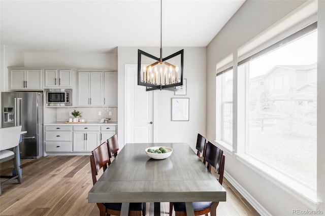 dining area with baseboards, a chandelier, and light wood-type flooring