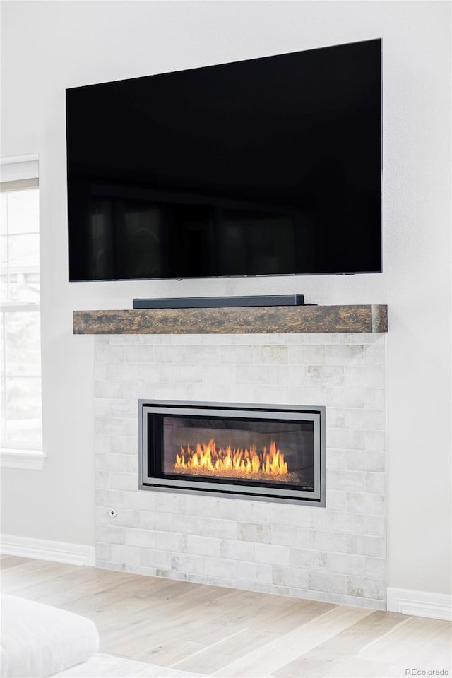 details featuring baseboards, a glass covered fireplace, and wood finished floors