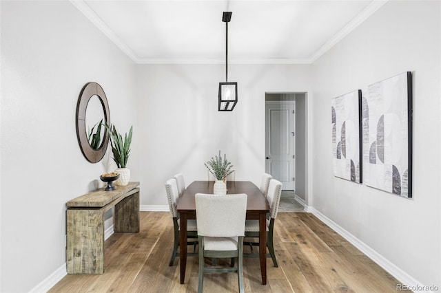dining room featuring baseboards, ornamental molding, and light wood finished floors
