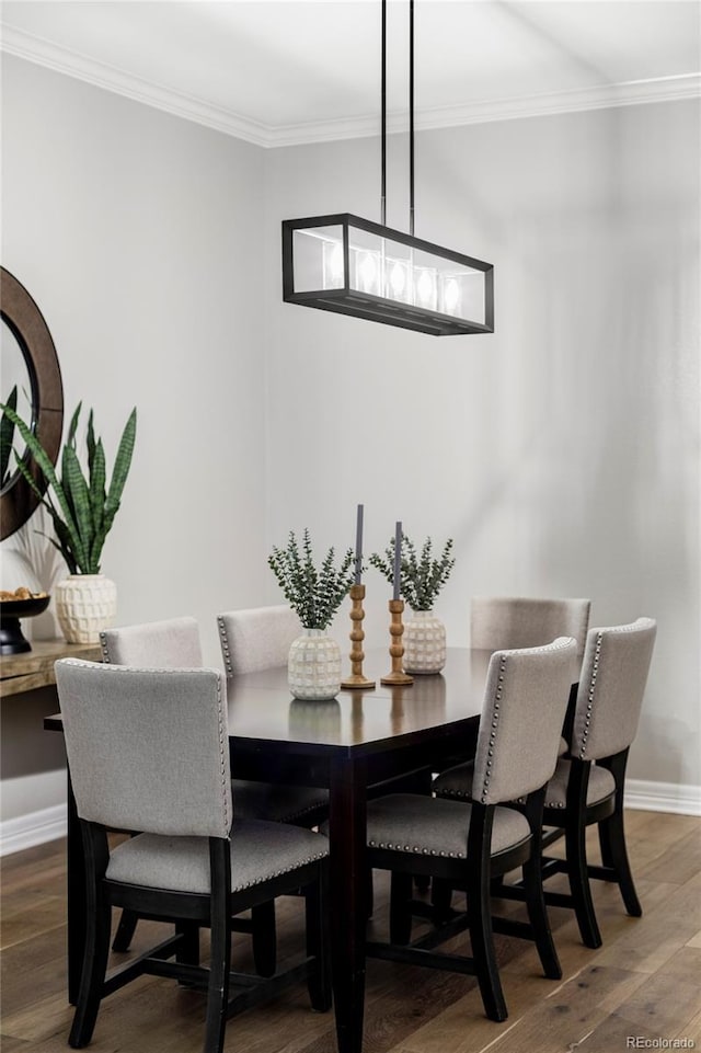 dining room featuring crown molding, baseboards, and wood finished floors