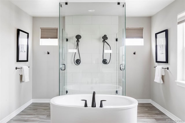 bathroom with a freestanding tub, baseboards, a stall shower, and wood finished floors