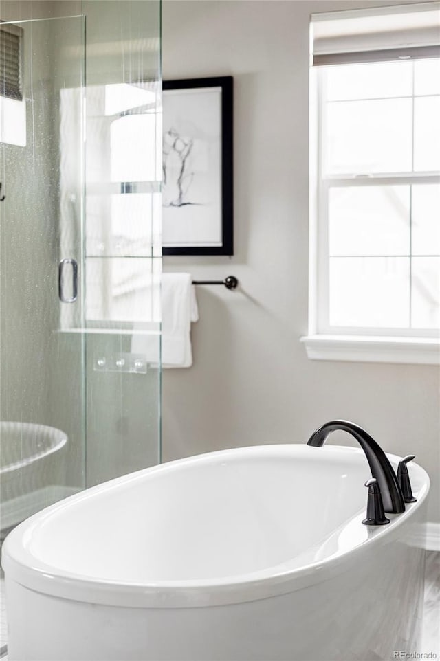 full bathroom featuring a shower stall, plenty of natural light, and a soaking tub