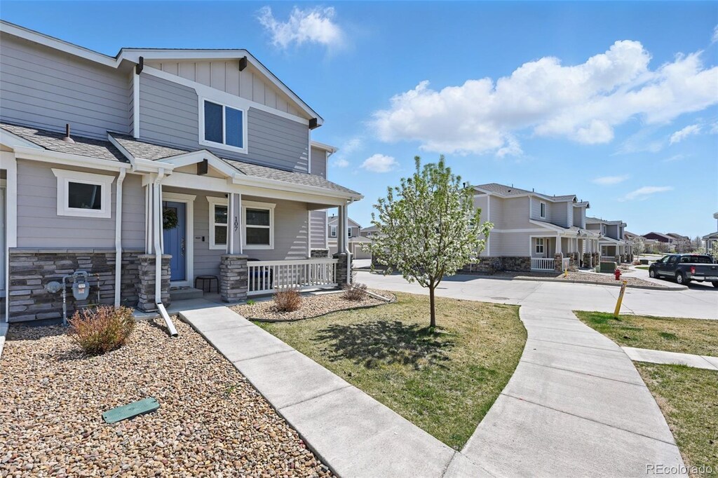 6113 Summit Peak Ct Unit 107, Erie, CO 80516 - craftsman inspired home with a residential view, board and batten siding, stone siding, a front yard, and covered porch