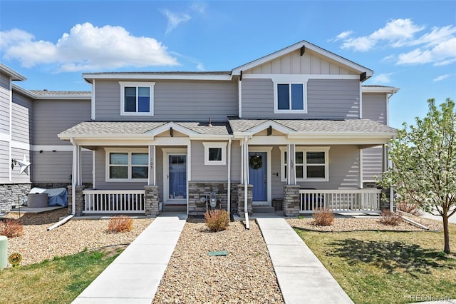 craftsman-style home with a porch, roof with shingles, board and batten siding, and stone siding