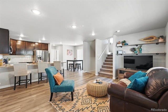 living room featuring light wood-style flooring, recessed lighting, baseboards, and stairway