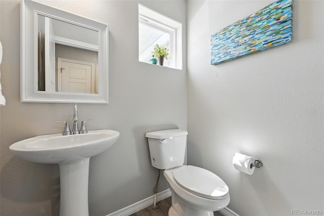 bathroom with toilet, wood finished floors, and baseboards