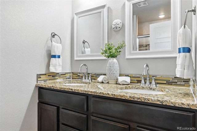 full bath featuring double vanity, visible vents, a sink, and backsplash
