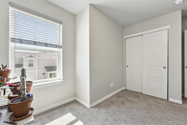 carpeted bedroom with a closet and baseboards