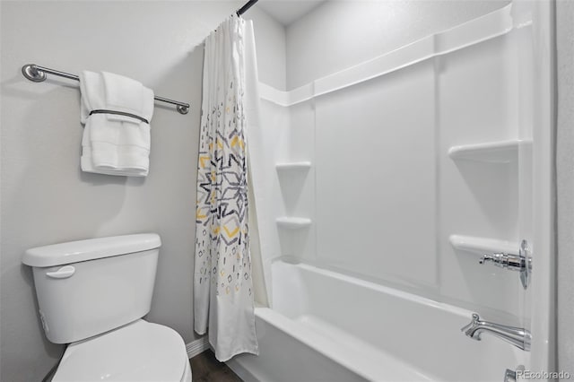 bathroom with toilet, shower / tub combo, wood finished floors, and baseboards