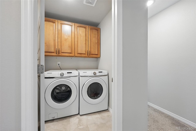 washroom with visible vents, baseboards, washing machine and clothes dryer, and cabinet space